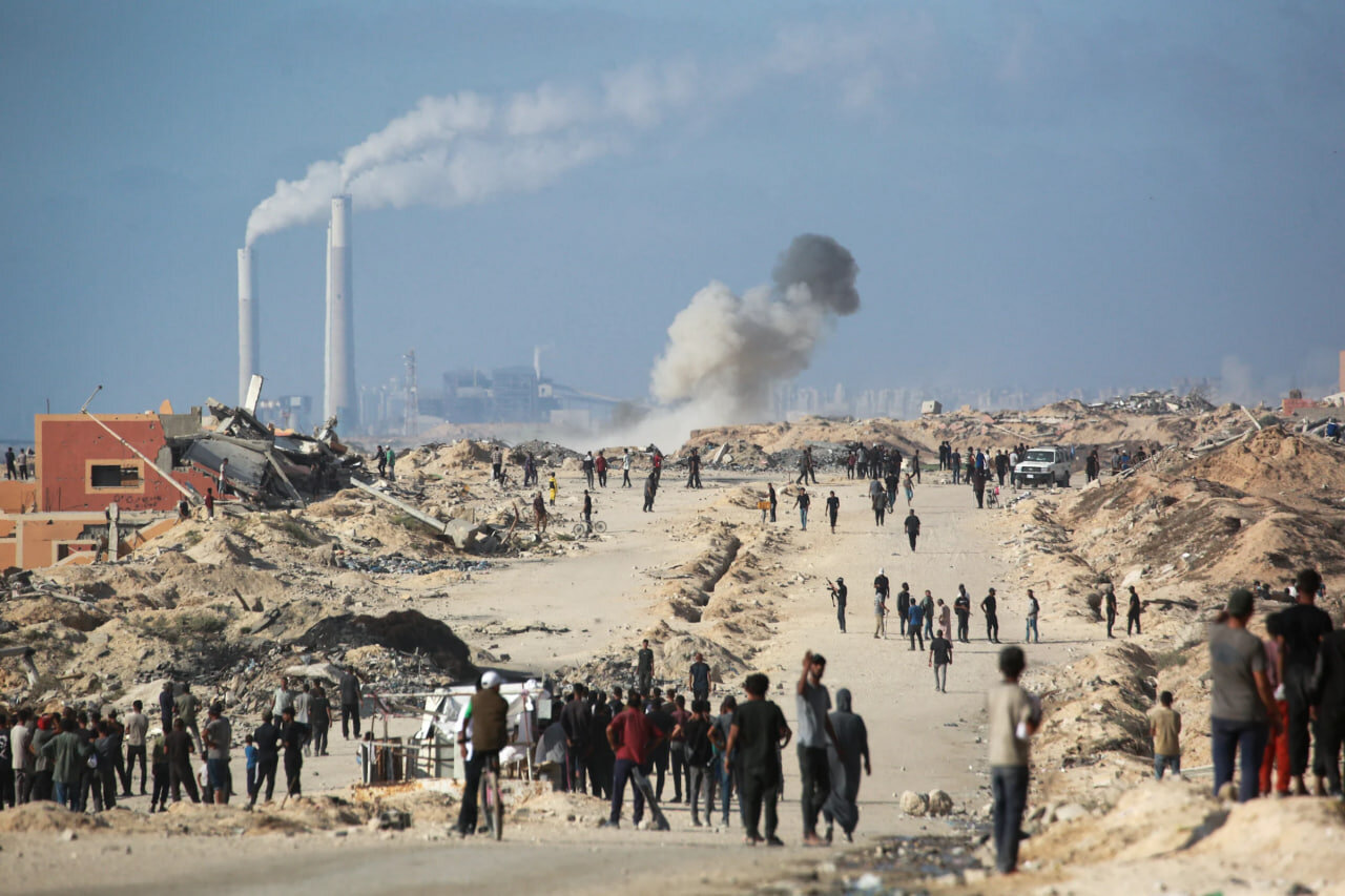Displaced people watch volunteers from Palestinian families organising to prevent theft from trucks carrying aid for the Gaza Strip from the Israeli-controlled Zikim crossing in northern Gaza on June