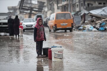 A displaced Palestinian child looks on amid a rainstorm in the western Gaza Strip, December 27, 2025 (AA)