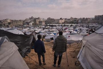 Palestinians look over makeshift tents of a camp for displaced people, set up in an area of Gaza City, on December 30, 2025 (AP)