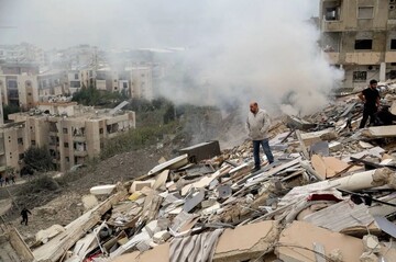 People inspect the damage of a building that was destroyed by an Israeli air raid on the southern Lebanese village of Qnarit on January 22, 2026