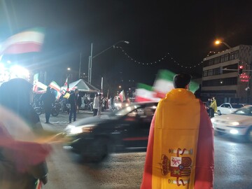 At Tehran’s Valiasr intersection, a man drapes himself in Spain’s flag during nightly rallies, a gesture of gratitude for Spain’s opposition to the US–Israel war on Iran