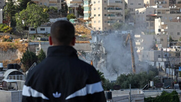 A man watches Israeli forces demolish a Palestinian-owned residential building in occupied al-Quds on 6 October 2026 (Ahmad Gharabli/AFP)