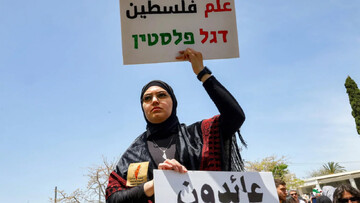 A demonstrator holds Arabic and Hebrew signs saying 'Palestine Flag' and 'Returning' during a Nakba Remembrance Day ceremony at Tel Aviv University on 13 May 2026 (Jack Guez/AFP)